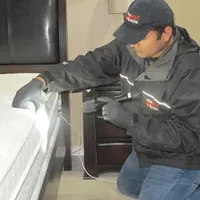 Bed bug inspection technician checking a mattress and bed frame for signs of infestation in Minneapolis, MN
